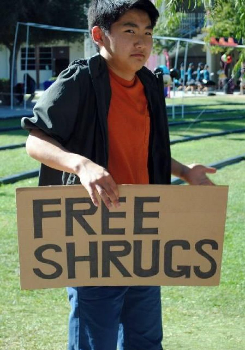 person holding a sign that says free shrugs